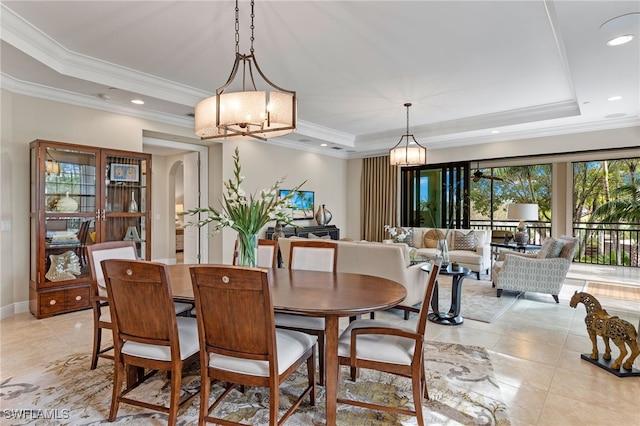 tiled dining room featuring a raised ceiling and crown molding