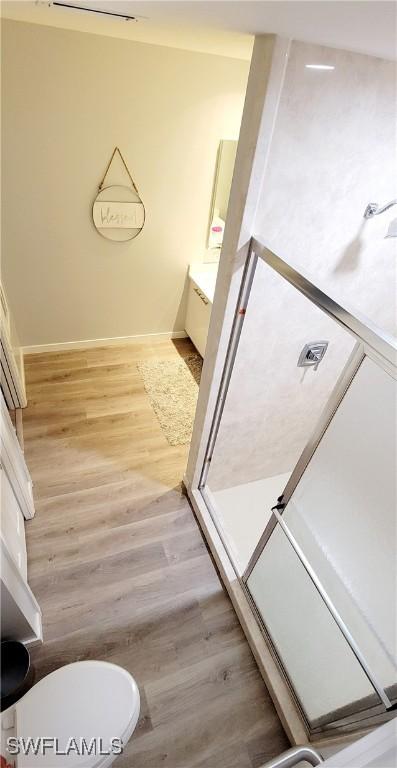 bathroom featuring hardwood / wood-style floors, vanity, toilet, and a shower with shower door