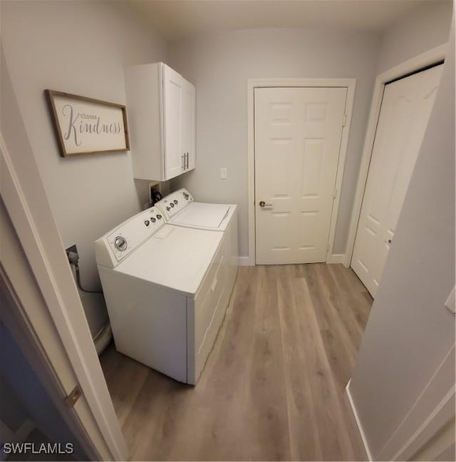 clothes washing area featuring washer and dryer, cabinets, and light wood-type flooring