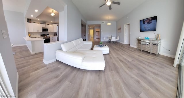 living room featuring ceiling fan, sink, and light hardwood / wood-style flooring