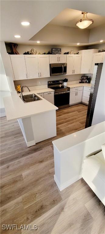 kitchen featuring white cabinetry, sink, black electric range, white refrigerator, and light wood-type flooring