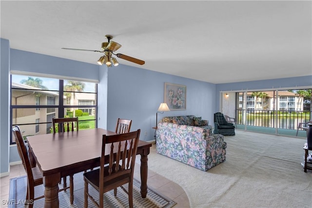 dining area featuring ceiling fan, a water view, and light carpet