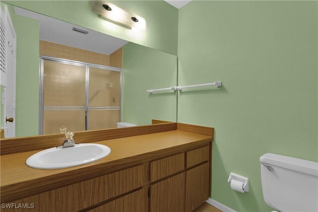 bathroom with a shower with door, vanity, and toilet