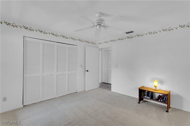 unfurnished bedroom featuring ceiling fan, a closet, and light colored carpet