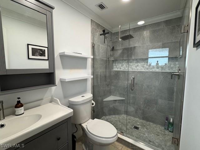 bathroom featuring toilet, ornamental molding, a shower with shower door, and vanity