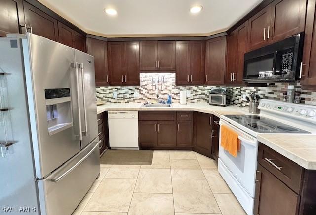 kitchen featuring white appliances, light tile patterned floors, decorative backsplash, dark brown cabinets, and sink