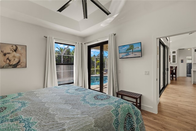 bedroom featuring a raised ceiling, access to exterior, ceiling fan, and light hardwood / wood-style floors