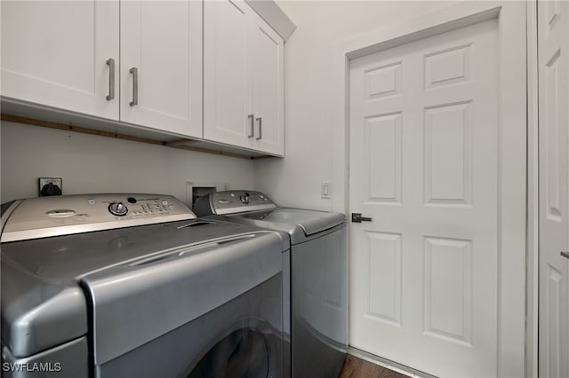 laundry room with washing machine and dryer, cabinets, and dark hardwood / wood-style floors