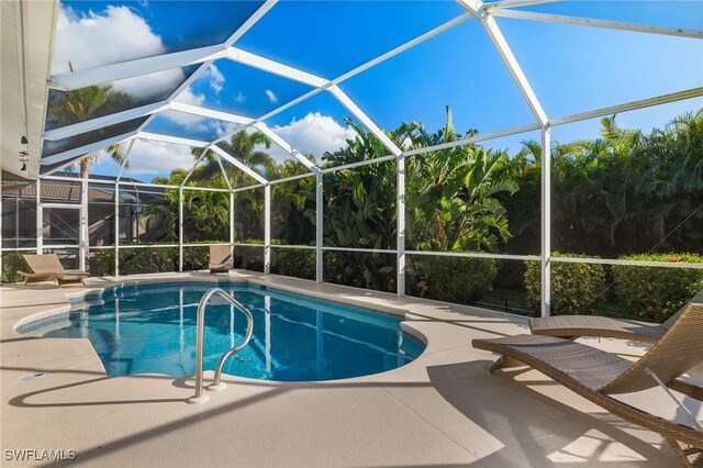 view of pool featuring glass enclosure and a patio