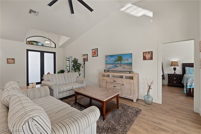 living room with ceiling fan, light hardwood / wood-style flooring, high vaulted ceiling, and french doors