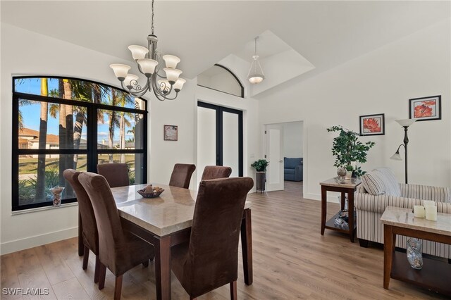 dining room with hardwood / wood-style floors, vaulted ceiling, and a notable chandelier