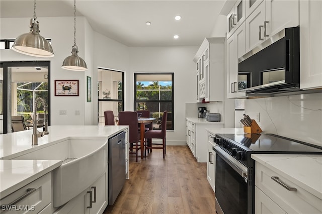 kitchen with a healthy amount of sunlight, white cabinets, pendant lighting, and appliances with stainless steel finishes