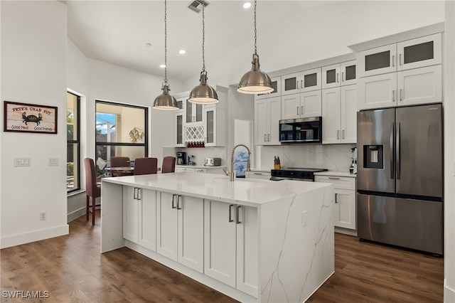 kitchen featuring white cabinetry, hanging light fixtures, light stone counters, an island with sink, and appliances with stainless steel finishes