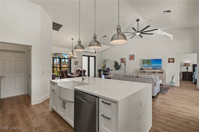 kitchen with sink, light stone counters, stainless steel dishwasher, a kitchen island with sink, and white cabinets