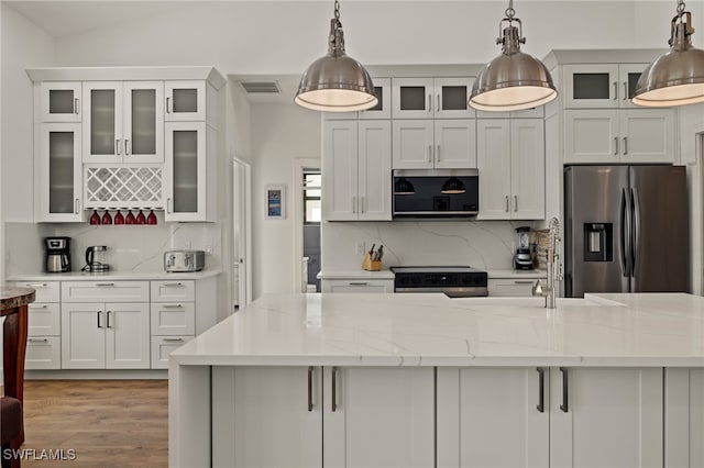 kitchen with decorative backsplash, light stone countertops, hanging light fixtures, and stainless steel appliances