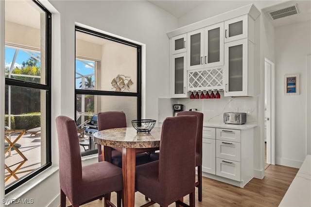 dining area featuring bar area and light hardwood / wood-style floors