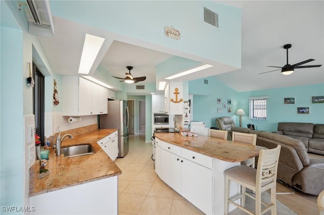 kitchen featuring a kitchen breakfast bar, sink, light stone countertops, white cabinetry, and stainless steel fridge with ice dispenser