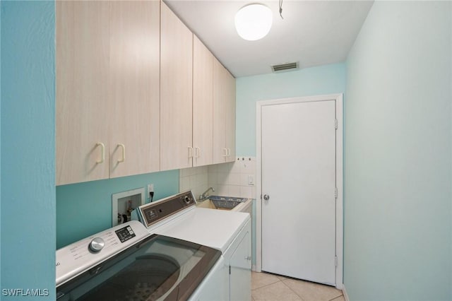 washroom with washing machine and dryer, sink, light tile patterned flooring, and cabinets