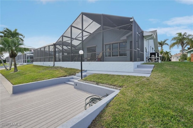 rear view of house with glass enclosure and a lawn