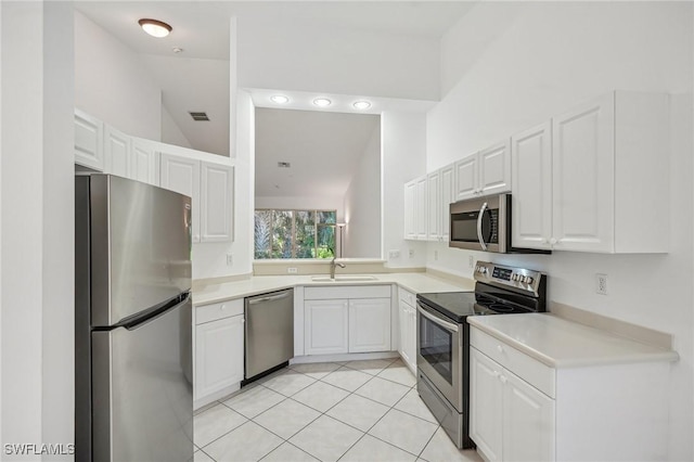 kitchen with sink, stainless steel appliances, light tile patterned floors, vaulted ceiling, and white cabinets