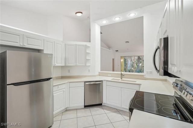 kitchen with stainless steel appliances, sink, light tile patterned floors, white cabinetry, and lofted ceiling