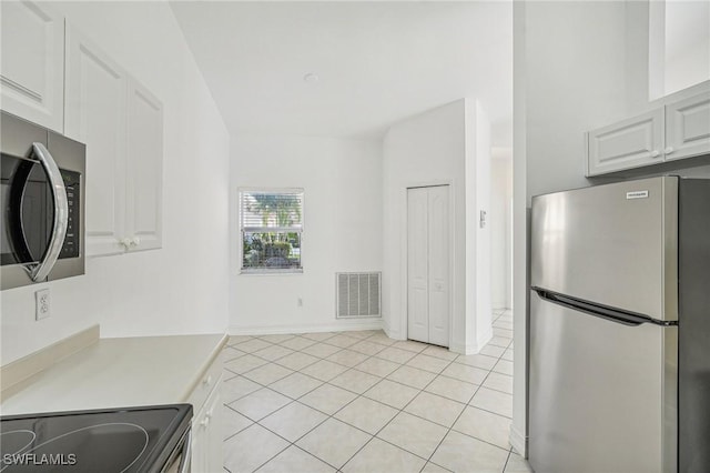 kitchen with light tile patterned floors, stainless steel appliances, and white cabinetry