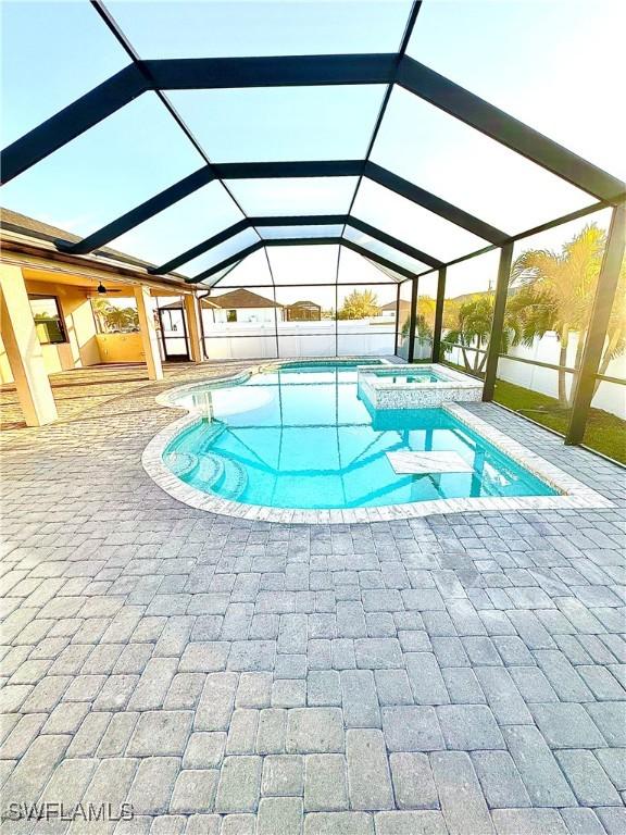 view of pool with a patio, an in ground hot tub, and glass enclosure