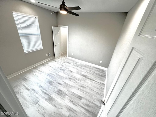 empty room with lofted ceiling, ceiling fan, and light wood-type flooring