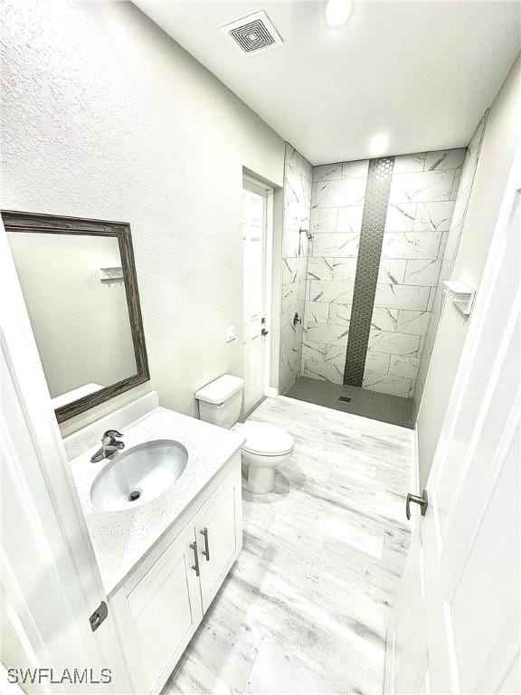 bathroom featuring vanity, toilet, and tiled shower