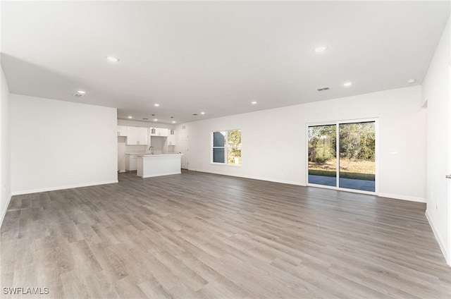 unfurnished living room with light hardwood / wood-style flooring and sink