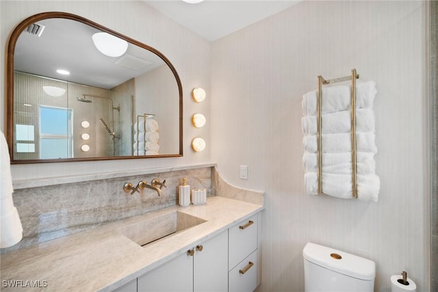 bathroom featuring tiled shower, vanity, and toilet