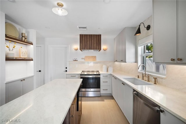 kitchen featuring sink, light hardwood / wood-style flooring, range hood, tasteful backsplash, and stainless steel appliances