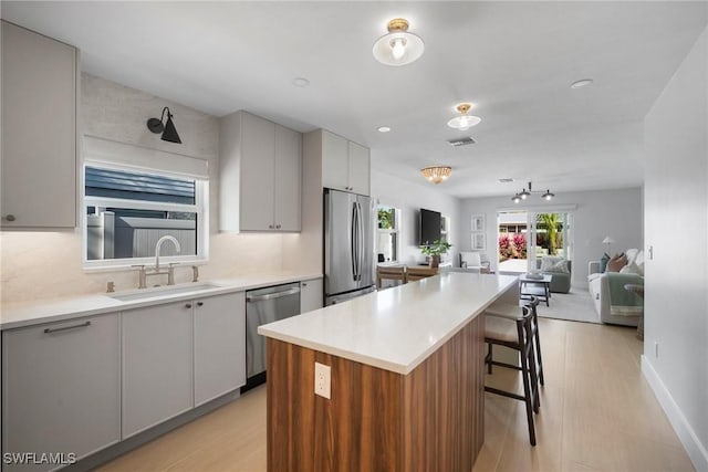 kitchen featuring a kitchen breakfast bar, sink, appliances with stainless steel finishes, tasteful backsplash, and a kitchen island