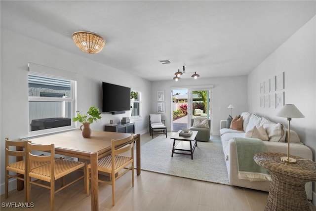 living room with light hardwood / wood-style floors and a notable chandelier