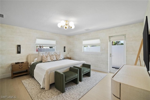 bedroom with multiple windows, light hardwood / wood-style flooring, and a chandelier