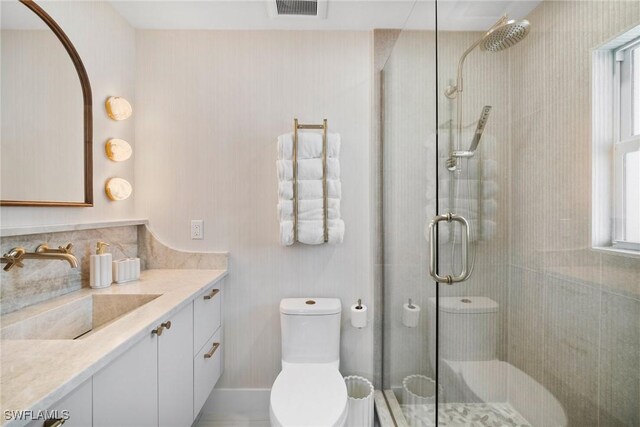 bathroom with plenty of natural light, vanity, a shower with shower door, and toilet