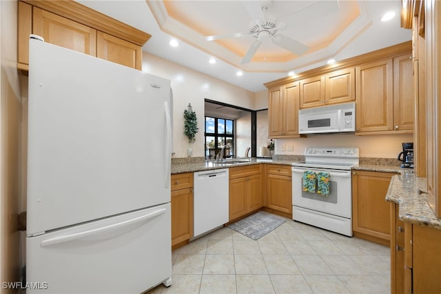 kitchen with white appliances, a raised ceiling, sink, ceiling fan, and light stone counters