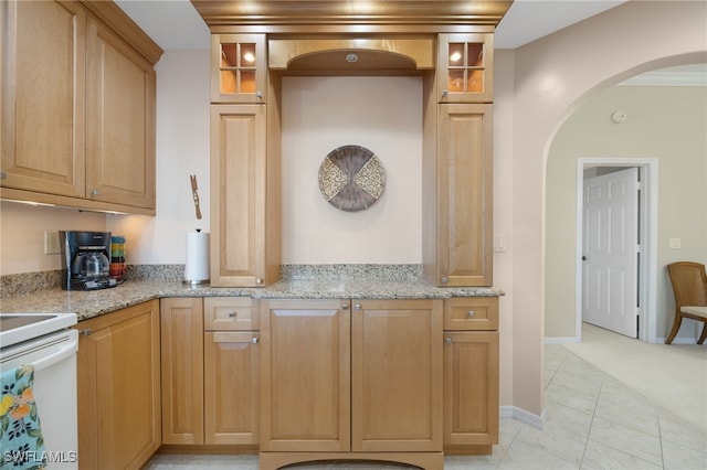 kitchen featuring light stone counters, stove, light tile patterned floors, and ornamental molding