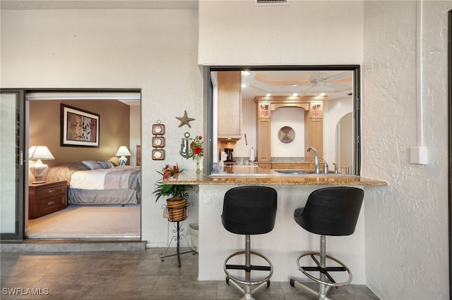 interior space with ceiling fan, sink, kitchen peninsula, and a breakfast bar area