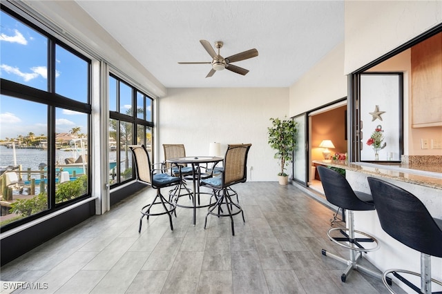 interior space with ceiling fan, a water view, and a healthy amount of sunlight