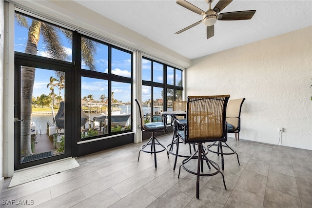 sunroom / solarium with ceiling fan and a water view