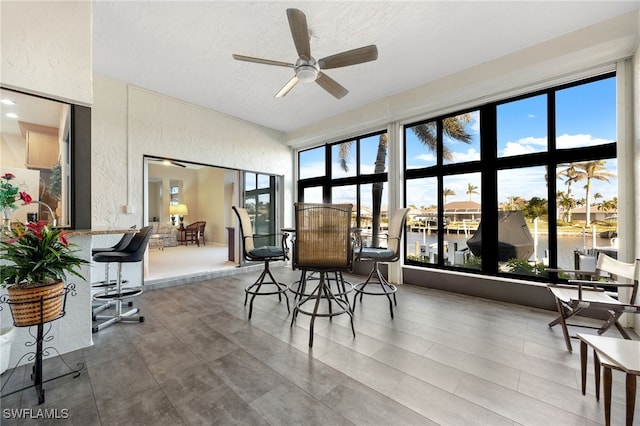 sunroom featuring a water view, plenty of natural light, and ceiling fan