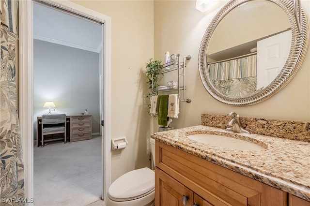 bathroom with toilet, vanity, and ornamental molding