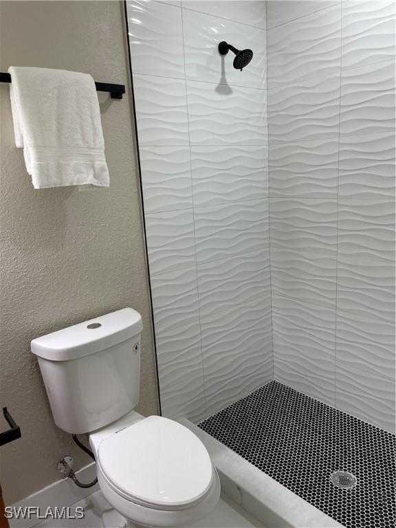 bathroom featuring toilet and a tile shower