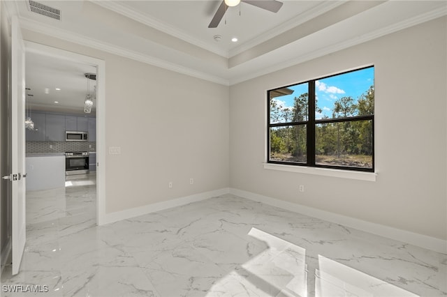 spare room with a tray ceiling, crown molding, and ceiling fan