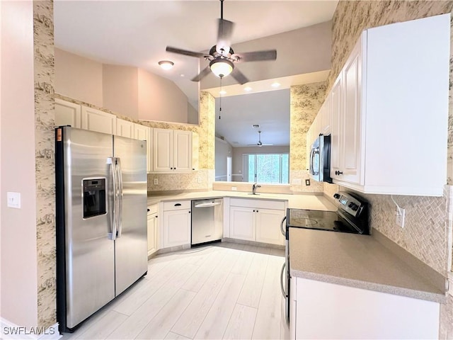 kitchen featuring tasteful backsplash, white cabinets, lofted ceiling, and appliances with stainless steel finishes