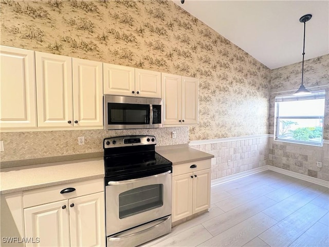 kitchen featuring white cabinetry, pendant lighting, light wood-type flooring, and appliances with stainless steel finishes