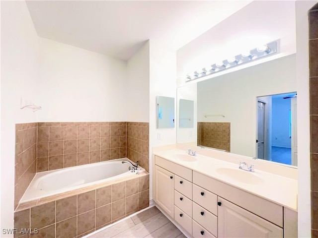 bathroom featuring tile patterned floors, tiled tub, and vanity