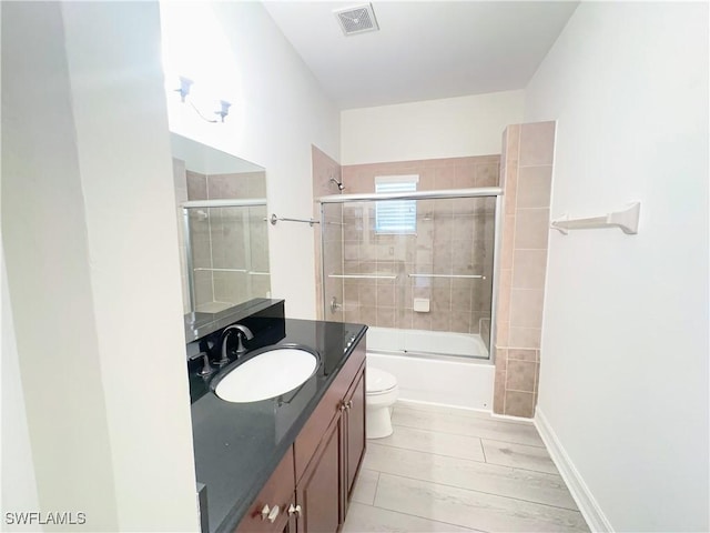 full bathroom featuring toilet, combined bath / shower with glass door, and vanity