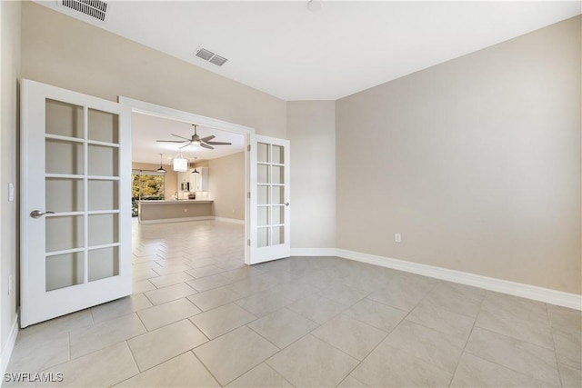 tiled spare room featuring ceiling fan and french doors